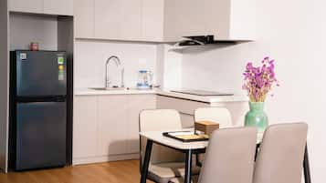Una cocina moderna con refrigerador, lavamanos y comedor con sillas y mesa.