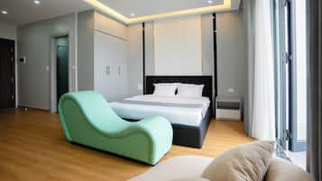 Un dormitorio moderno con una cama, un sillón curvo color turquesa y un ventanal grande.