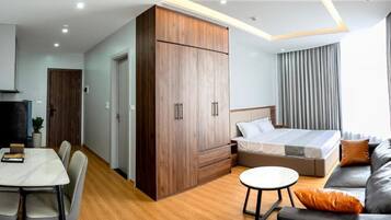 Una habitación de hotel moderna con cama, sofá, mesa de comedor y armario.