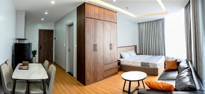 A modern hotel room with a bed, sofa, dining table, and a wardrobe. - Lumia Hotel Vinh Yen (Vĩnh Phúc)