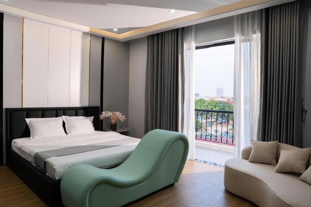 Habitació d'hotel amb llit, una cadira relaxant, un sofà, un balcó amb vistes i una finestra gran.