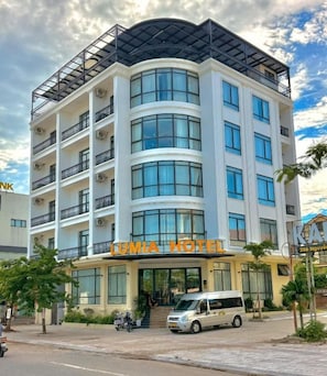 Un hotel de varios pisos con fachada curva, balcones y un letrero que dice 'LUMIA HOTEL'.