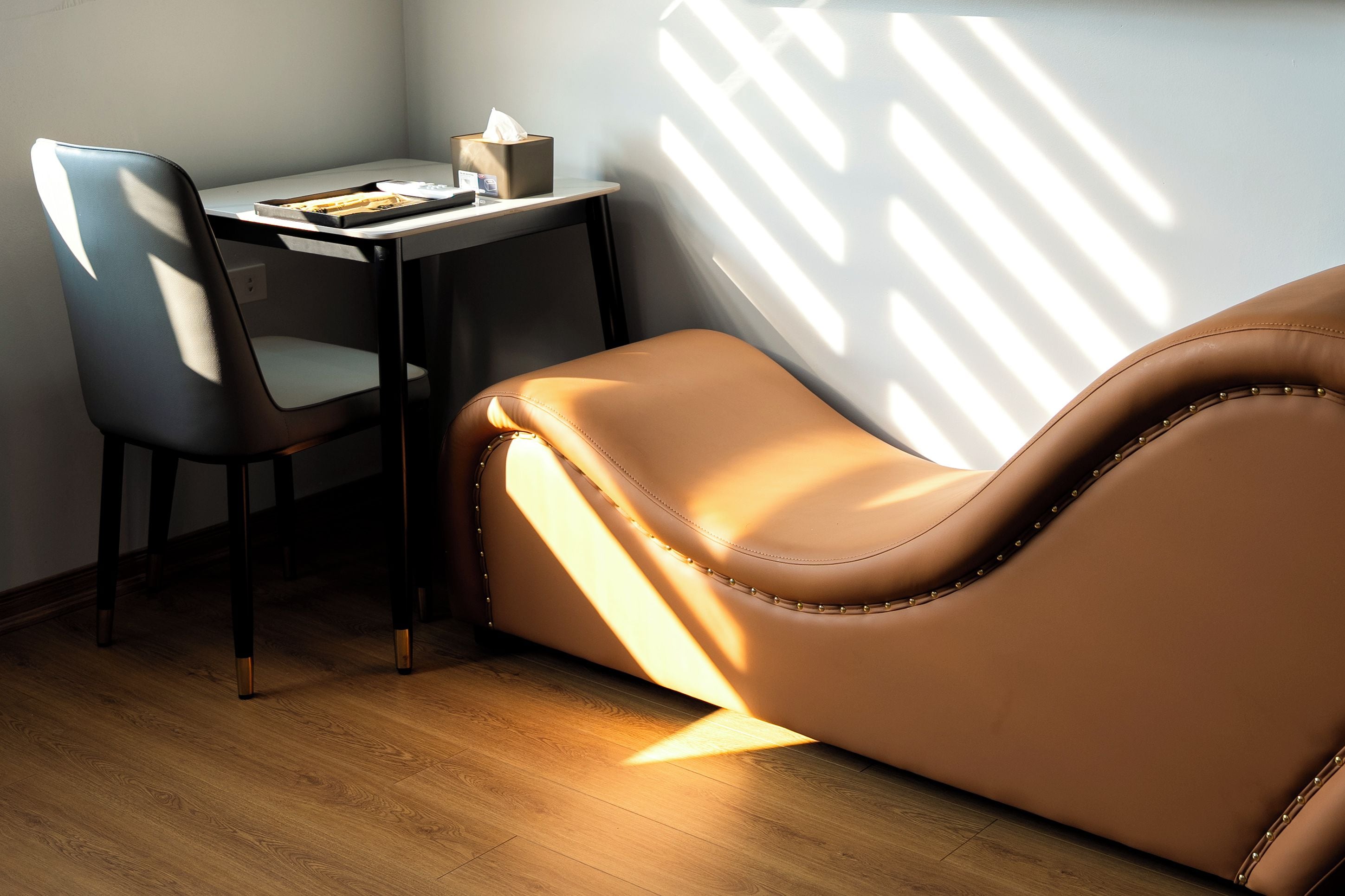A room with a leather sofa, a desk, and a chair.