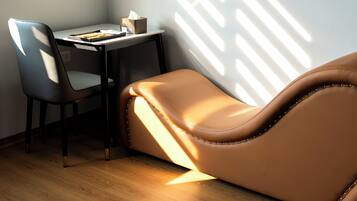 A room with a leather sofa, a desk, and a chair.