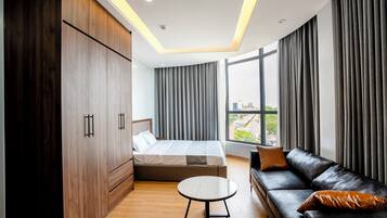 A modern hotel room with a bed, a sofa, a small table, and a wardrobe.