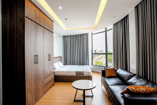 A modern hotel room with a bed, a sofa, a small table, and a wardrobe.