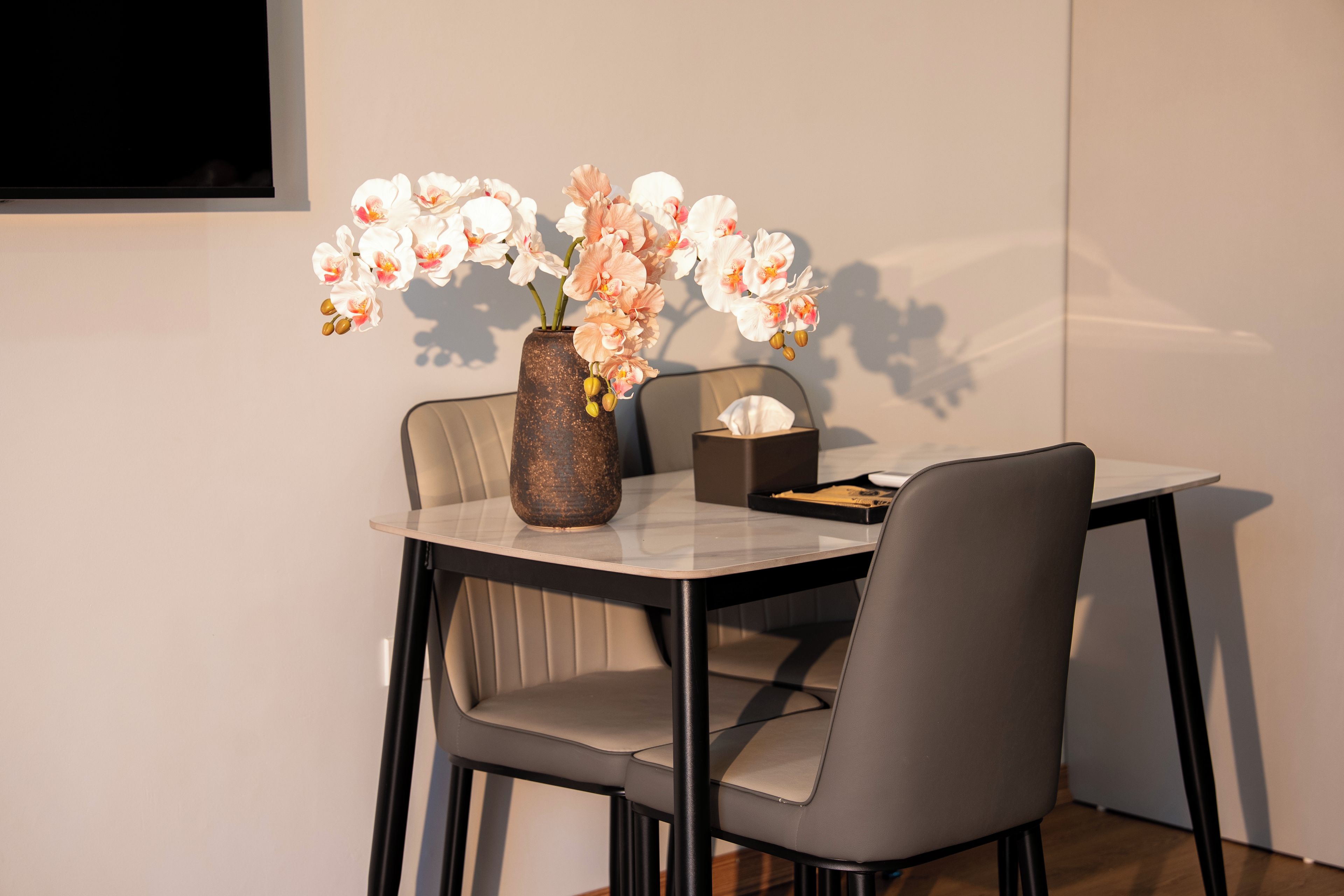A dining table with a vase of flowers, a tissue box, and a tray.