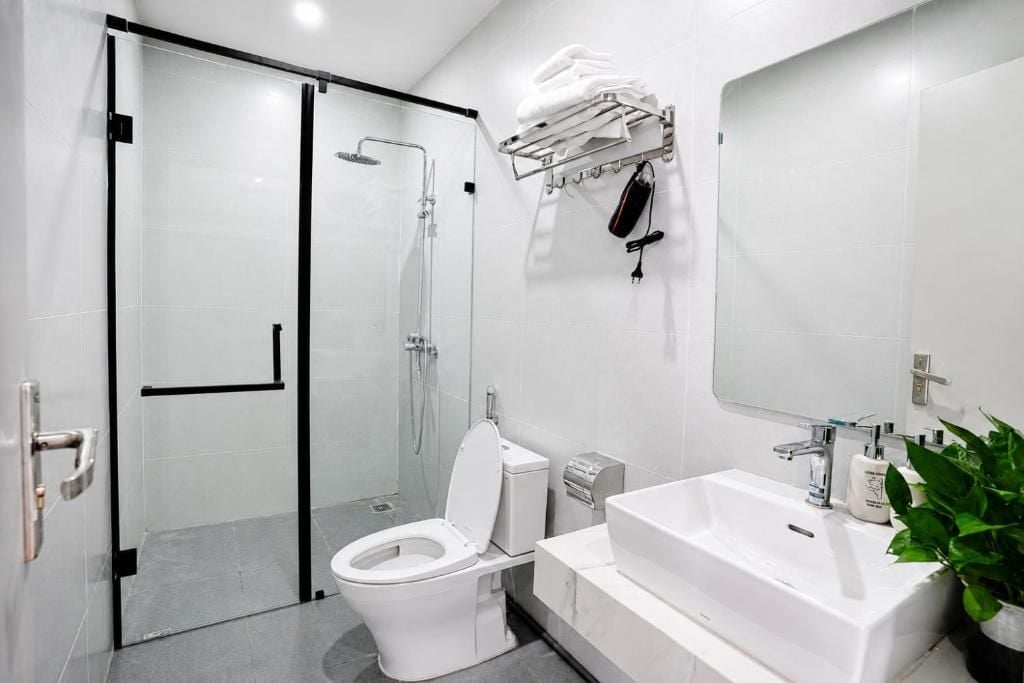 A modern bathroom with a glass-enclosed shower, a white toilet, a sink with a mirror, and a towel rack.