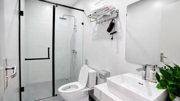 A modern bathroom with a glass-enclosed shower, a white toilet, a sink with a mirror, and a towel rack.