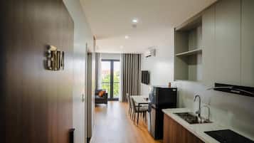 A modern kitchen with a built-in stove, a dining area with a table and chairs, and a view of the outdoors through a glass door.