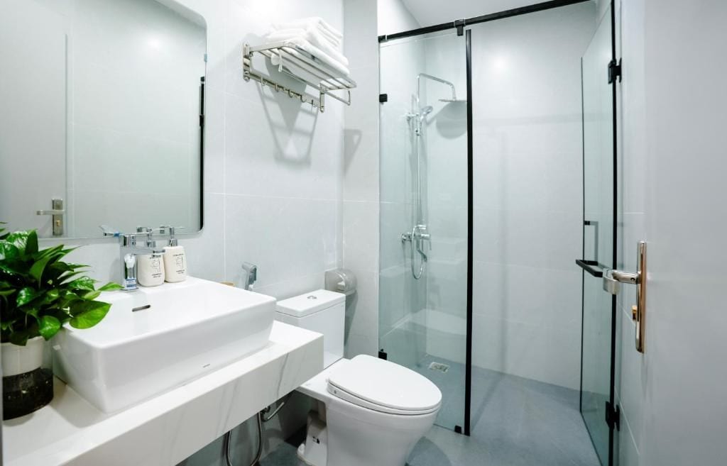 A modern bathroom with a glass shower enclosure, a white sink, and a toilet.