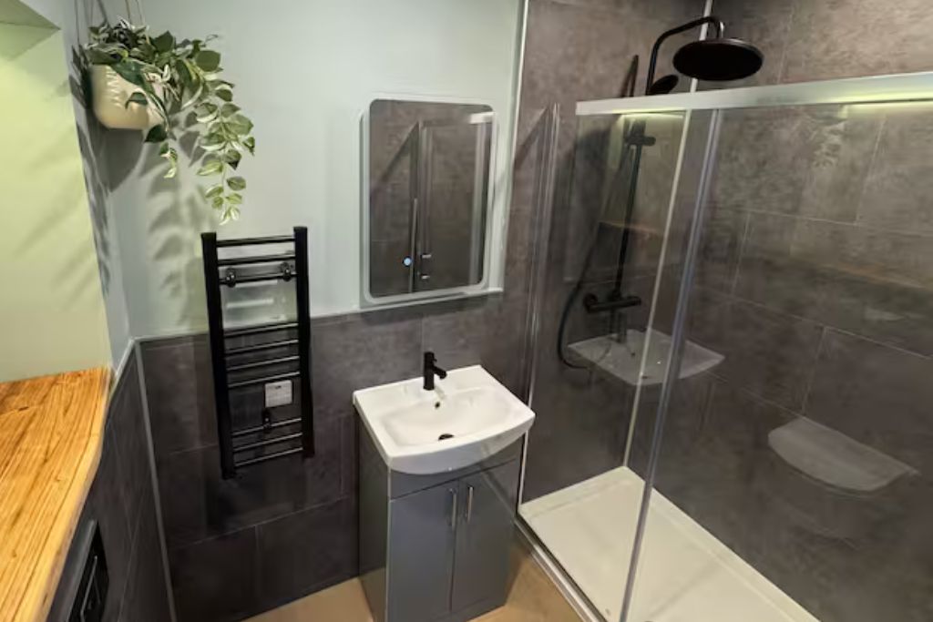 Ein modernes Badezimmer mit Duschkabine aus Glas, einem weißen Waschbecken und einem Handtuchhalter.