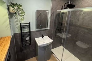 Ein modernes Badezimmer mit Duschkabine aus Glas, einem weißen Waschbecken und einem Handtuchhalter.