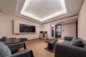 A modern interior with a flat-screen TV mounted on the wall, a small kitchenette, and a seating area with a table and chairs. - Howard Johnson Club Hotel Wuhan Jiyuqiao (Wuhan)