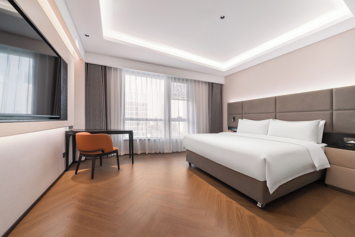 A modern hotel room with a bed, a desk, and a chair.