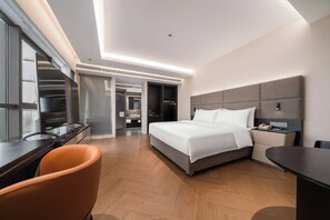 Una habitación de hotel moderna con cama, escritorio, silla y vestidor.