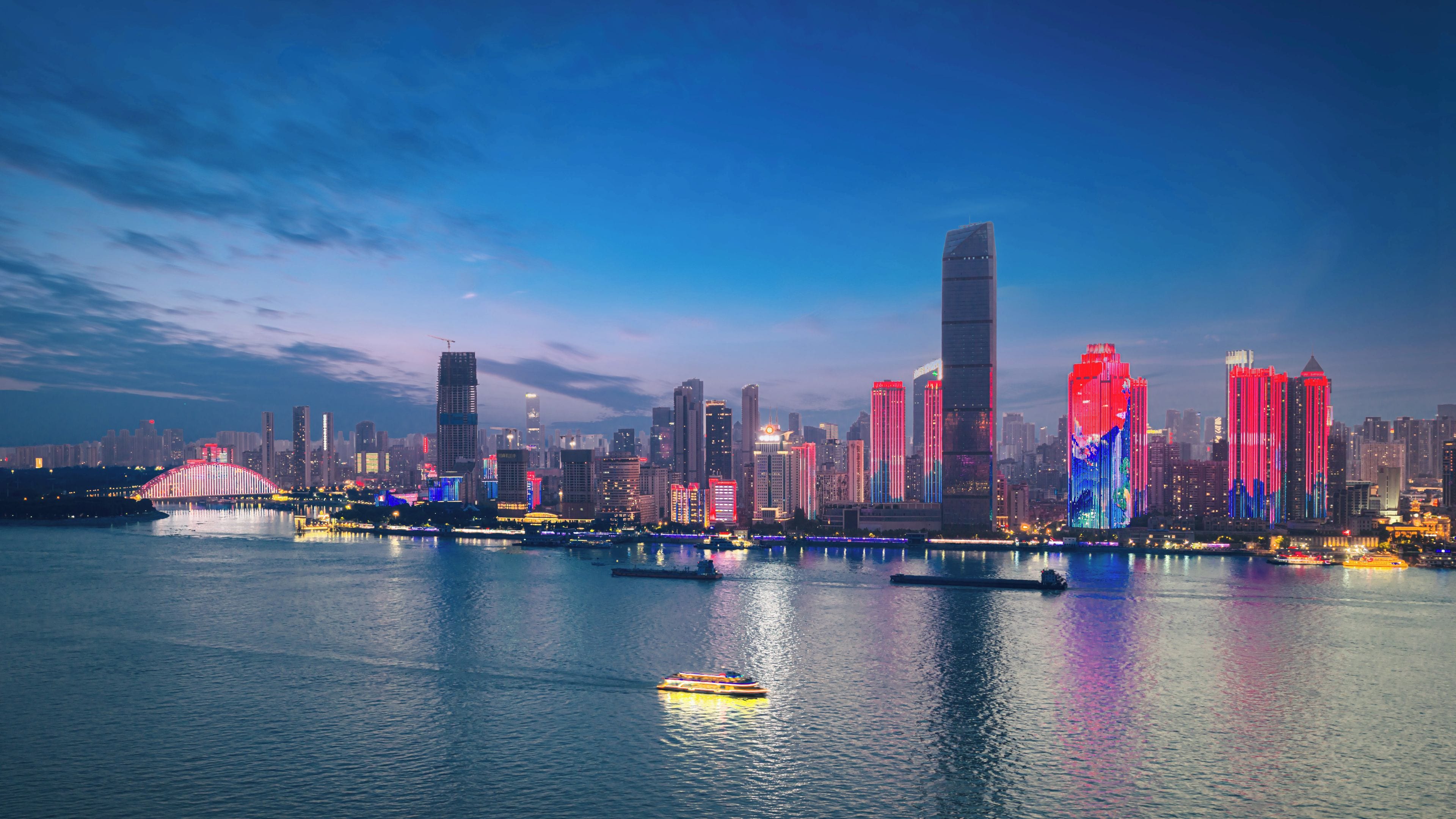 A city skyline with illuminated buildings along a river.