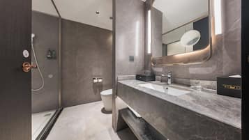 A modern bathroom with a marble vanity, a large mirror, a shower area, and a toilet.