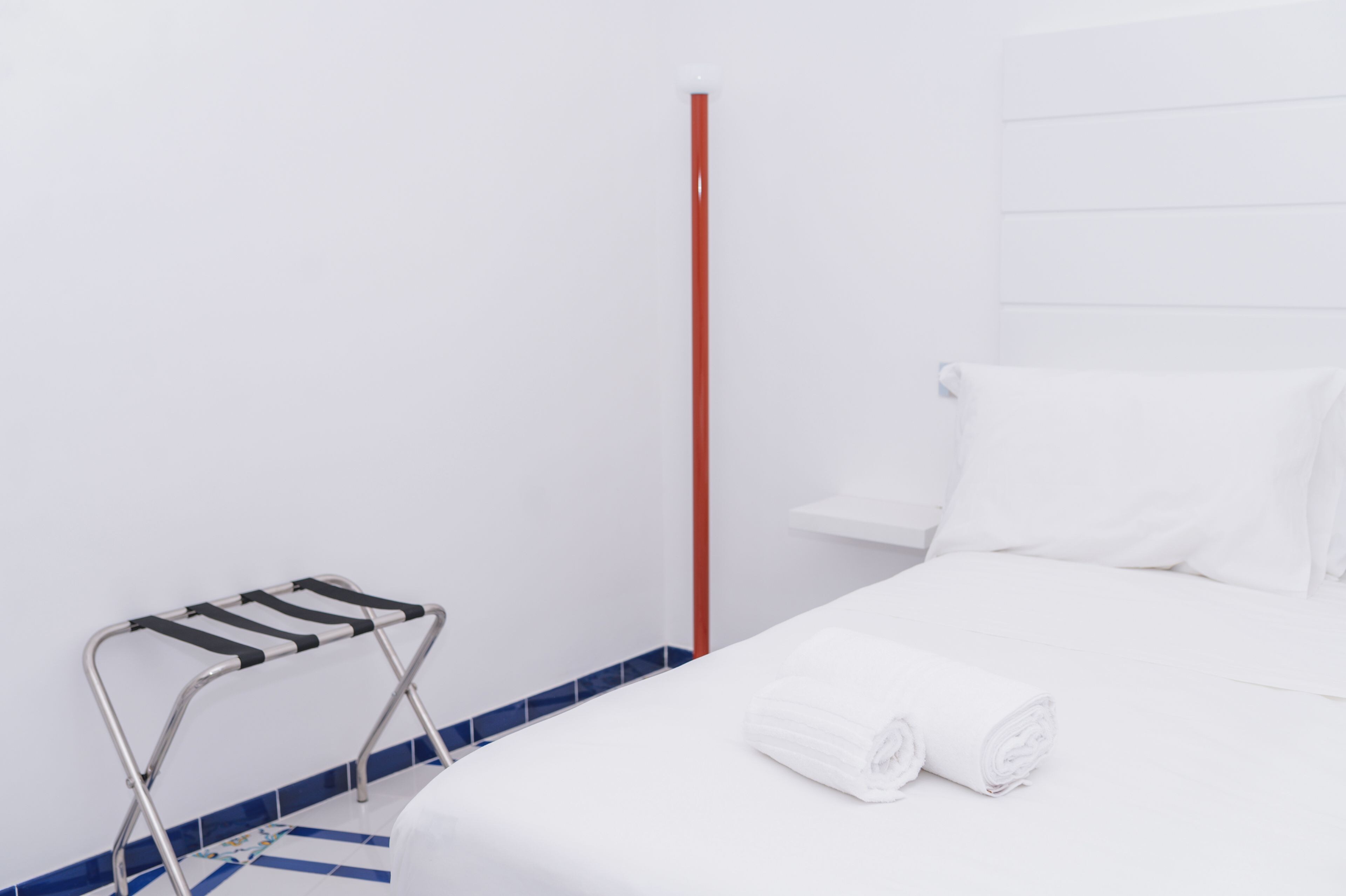 Une chambre d’hôtel avec un lit, un porte-serviettes et un poteau rouge.
