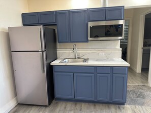 A compact kitchen with a stainless steel refrigerator, a microwave, and a sink. - Cozy  studio in welcoming Indio with AC (Indio)