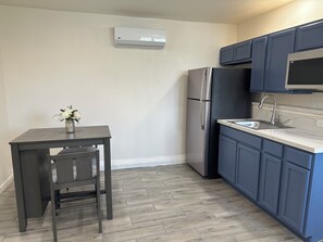 A compact kitchen with a refrigerator, a sink, and a dining table with chairs. - Cozy  studio in welcoming Indio with AC (Indio)