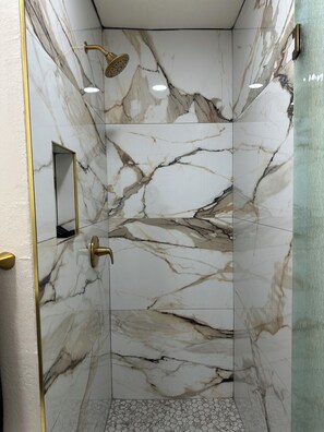 A shower with a gold shower head and a rectangular mirror on the wall. - Cozy  studio in welcoming Indio with AC (Indio)