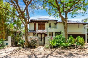 A two-story house with a tiled roof, surrounded by a garden with various plants and trees. - Far Pavilions Villa A - Luxe Hillside Escape (Port Douglas)