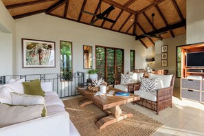 A spacious living area with a high ceiling, a dining set, and a television. - Far Pavilions Villa A - Luxe Hillside Escape (Port Douglas)