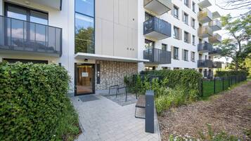 Ein modernes Apartmenthaus mit einer Steinfassade, mehreren Balkonen und einem geschlossenem Eingangsbereich.