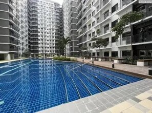A swimming pool surrounded by high-rise residential buildings with balconies. - MOA Complex 1BR Shore 3 tower 1 unit 547 (Pasay City)