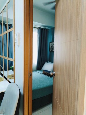 A room with a bed, a chair, a small table, and a window with curtains. - MOA Complex 1BR Shore 3 tower 1 unit 547 (Pasay City)