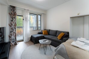 Ein modernes Zimmer mit einer Couch, einem Bett, einem kleinen Tisch und einem Fernseher.