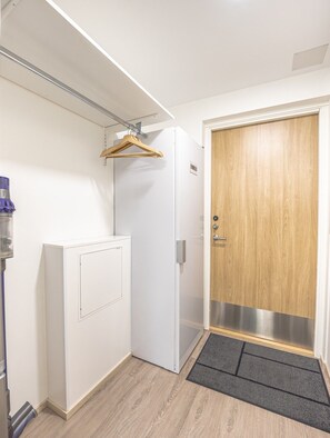 A hallway with a white door, a wooden door, a coat rack, and a doormat. - Levi South Studio 1, Private Sauna By Lapland Host (Levi)