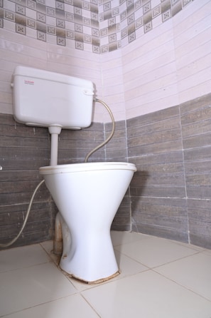 Inodoro con tanque y tubería, frente a una pared de azulejos con diseño.