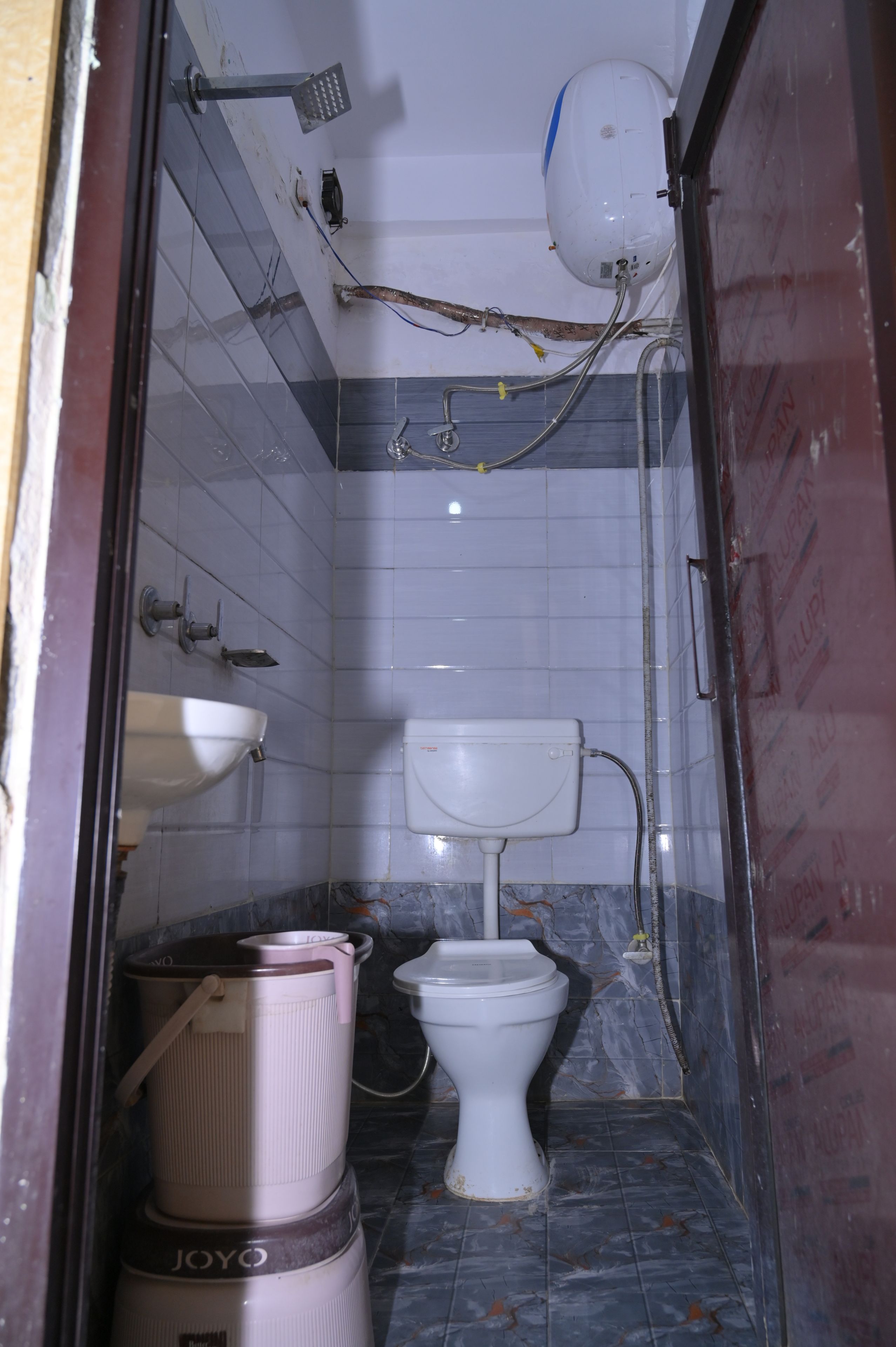 Un baño pequeño y estrecho con inodoro, lavamanos y ducha.