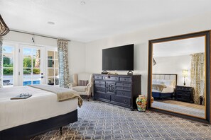 Un dormitorio de hotel con una cama grande, un aparador, un televisor y un espejo.
