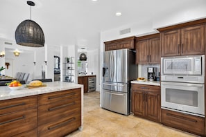 A modern kitchen with wooden cabinets, stainless steel appliances, and a marble countertop. - Private Pool + Hot Tub + Fire Pit + Covered Patio | Mins to Golf | Casa Talavera (Scottsdale)