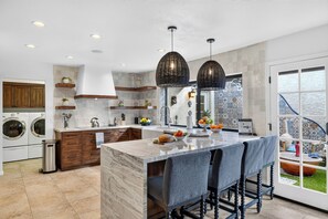 Una cocina moderna con una isla de mármol, armarios de madera y un amplio ventanal con vistas a un jardín.