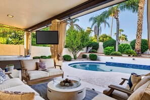 A poolside area with a sofa, a flat-screen TV, and a fire pit. - Private Pool + Hot Tub + Fire Pit + Covered Patio | Mins to Golf | Casa Talavera (Scottsdale)