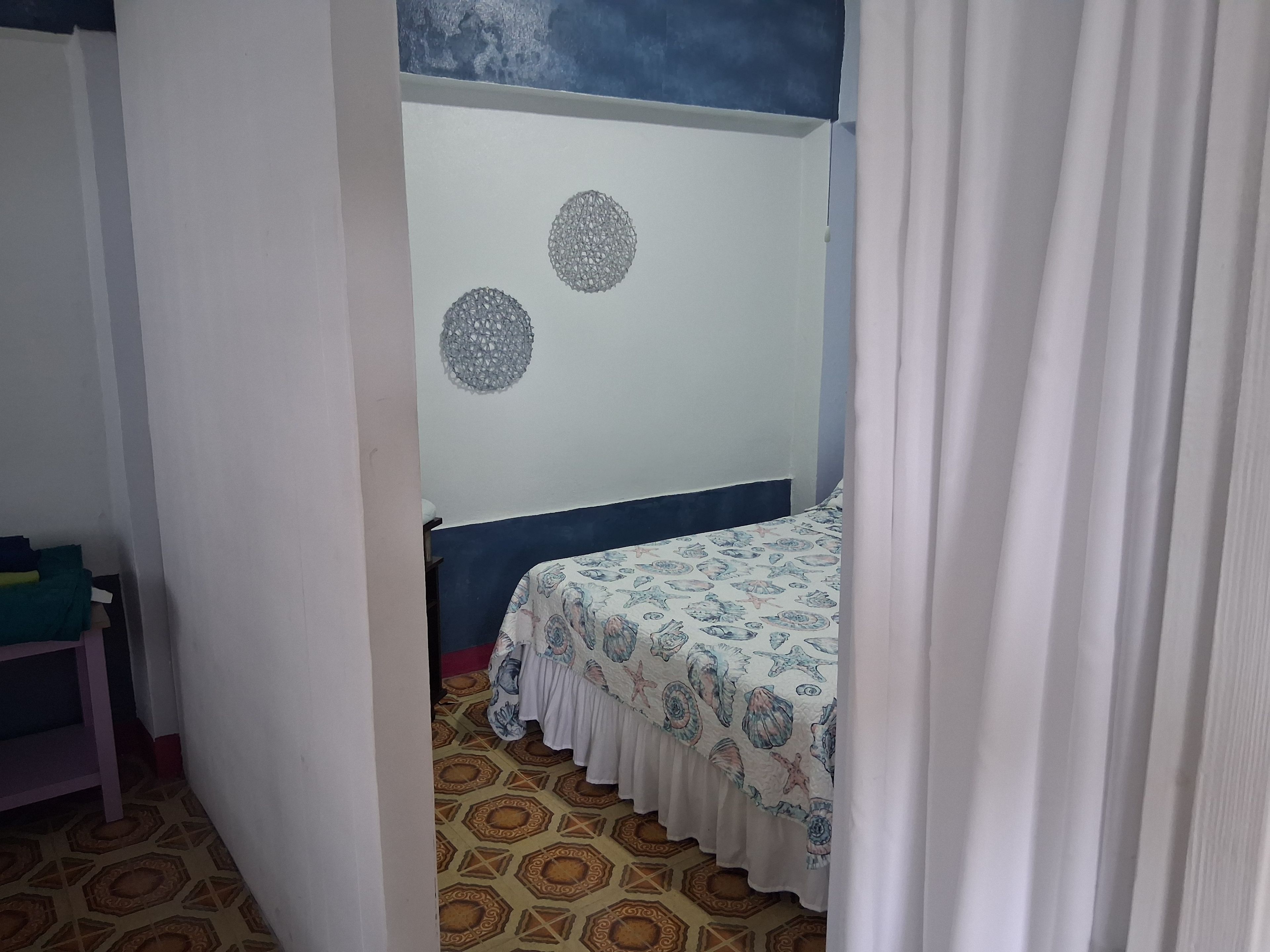 Una habitación con una cama, una alfombra estampada y una pared con adornos circulares.