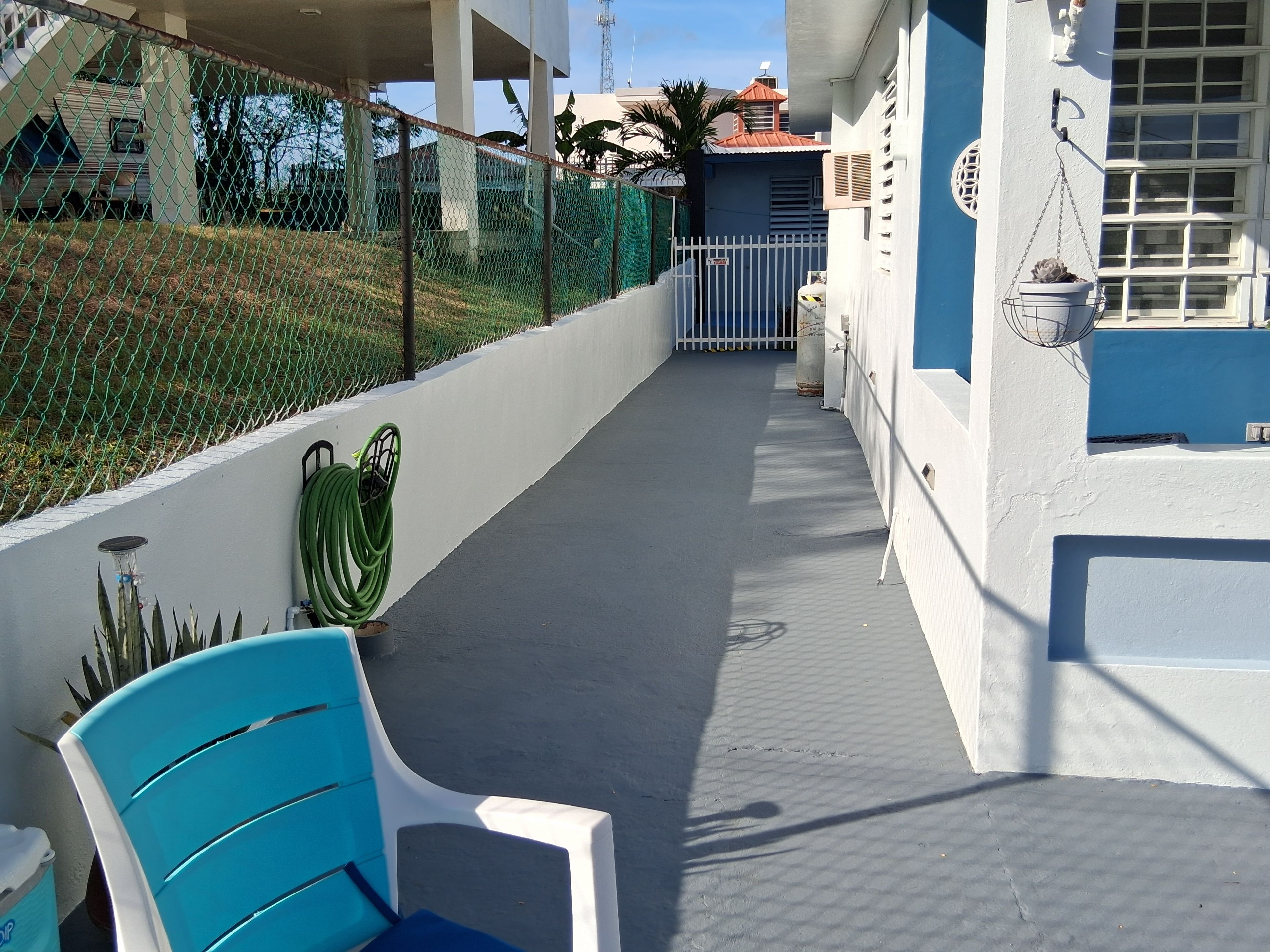 Un espacio al aire libre cubierto con una silla azul, una silla blanca y una planta en maceta.