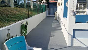 Un espacio al aire libre cubierto con una silla azul, una silla blanca y una planta en maceta.