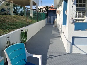 Un espacio al aire libre cubierto con una silla azul, una silla blanca y una planta en maceta.
