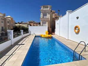 A swimming pool with a lifebuoy on the wall, a metal ladder, and a yellow inflatable float. - Villa in Nerja Near Burriana Beach (Nerja)