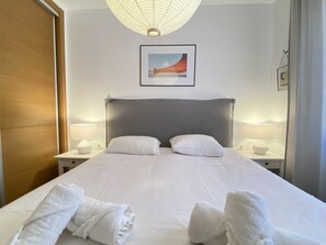 A hotel room with a large bed, two bedside tables with lamps, a wooden door, and a framed picture on the wall. - Villa in Nerja Near Burriana Beach (Nerja)