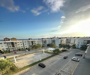Ein mehrstöckiges Wohngebäude mit Parkplatz, Bäumen und blauem Himmel.