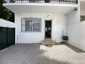 A building with a white exterior, a metal gate, a window with bars, and a door leading inside. - Holiday Home in Nerja Near Playa Carabeillo (Nerja)