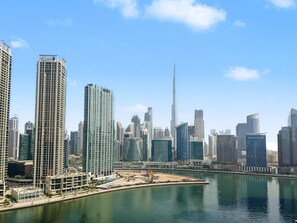 Eine Skyline mit modernen Hochhäusern, einem markanten Turm und einer Uferpromenade.