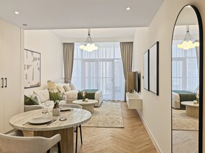 Ein modernes Wohnzimmer mit Essbereich, großen Fenstern und einem Spiegel.