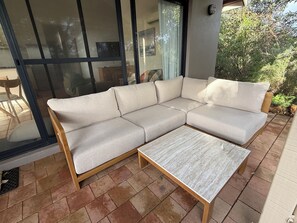 A sectional sofa with a wooden frame and a small table in front of a glass door.